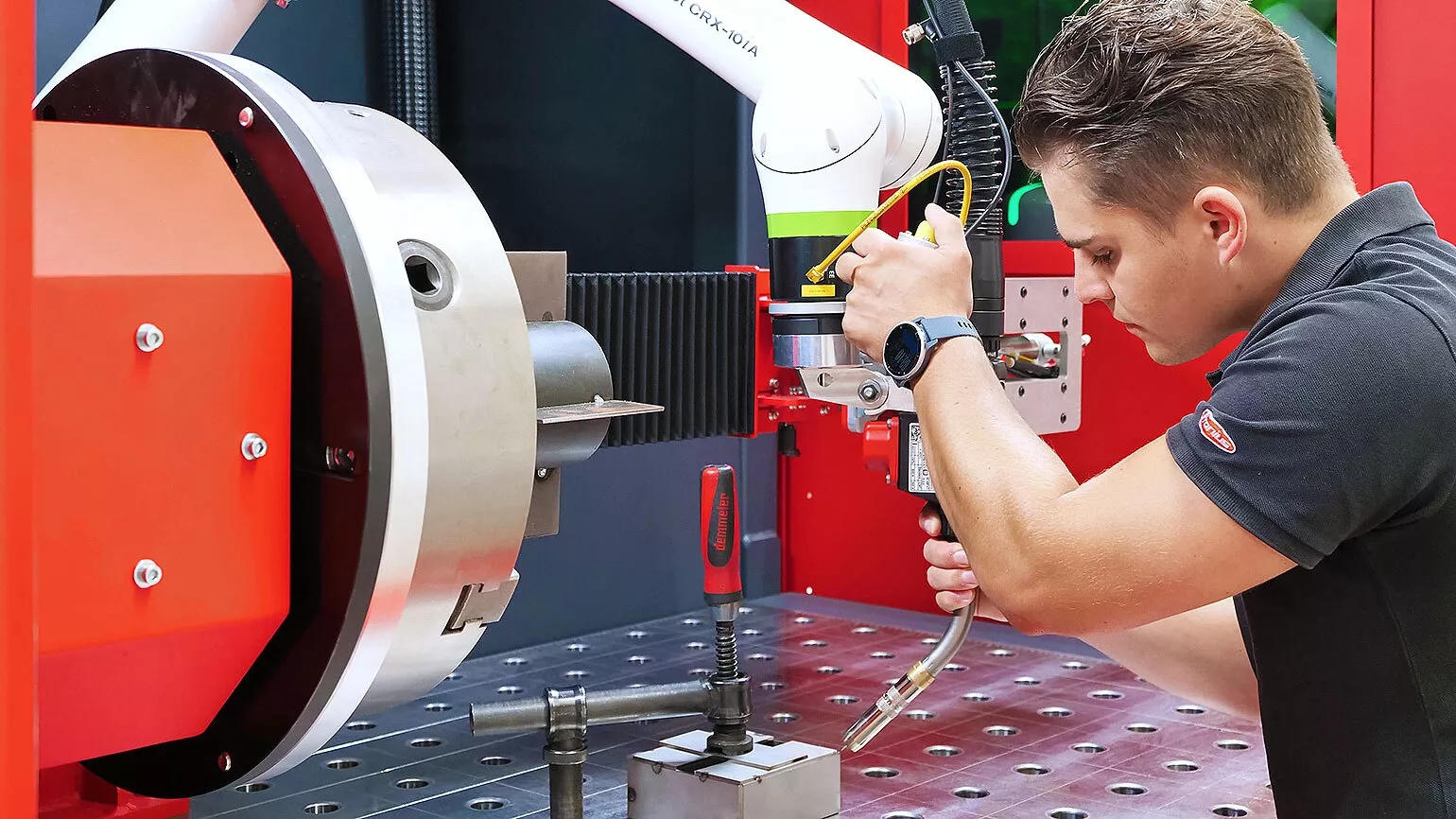 Man working with a Fronius cobot welding system.