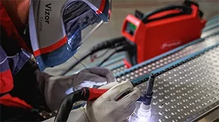 Person welding with protective helmet and gloves.