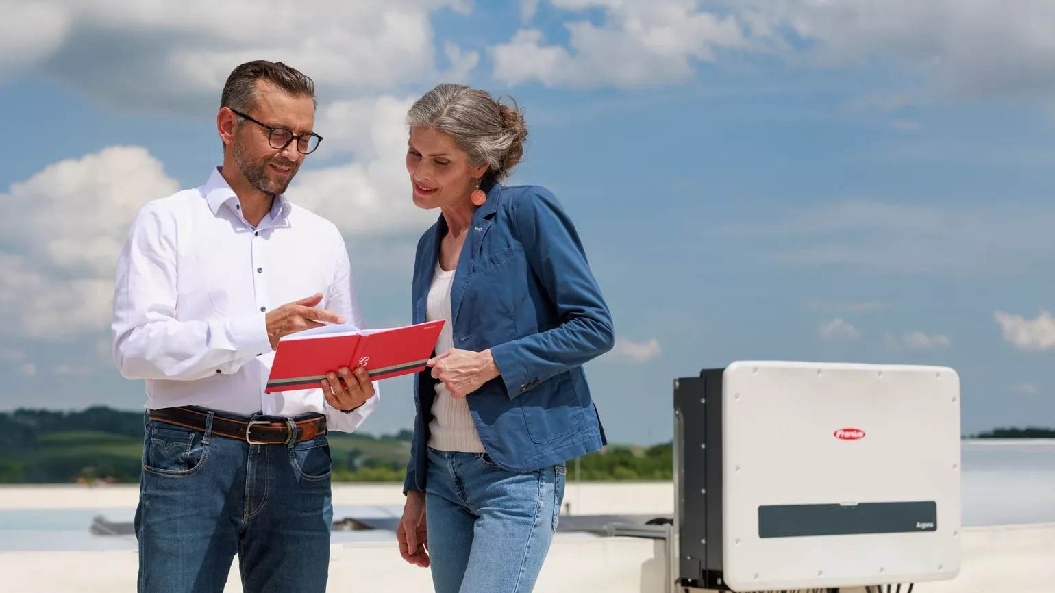 Twee mensen praten op het dakterras van een groot bedrijf over de voordelen van Fronius Argeno.