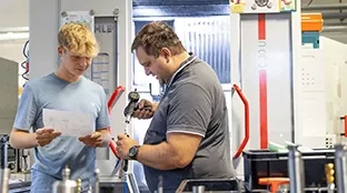 Ein Fronius Mitarbeiter erklärt einem Ferialjob-Mitarbeiter eine Aufgabe.